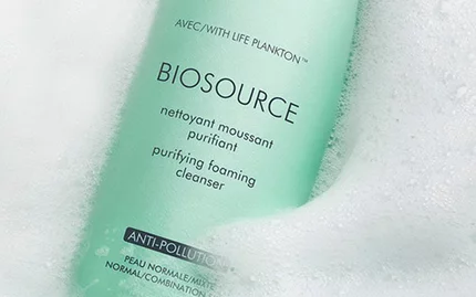 Biotherm Biosource purifying foaming cleanser bottle with Life Plankton, surrounded by soft foam bubbles.