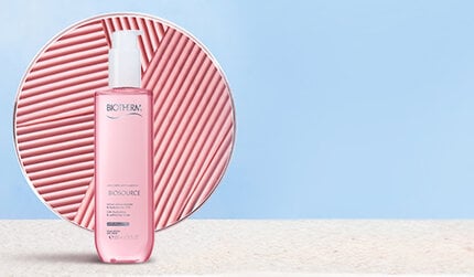 Biotherm pink Biosource bottle with pump placed on stone surface, against a circular pink textured background and light blue wall.