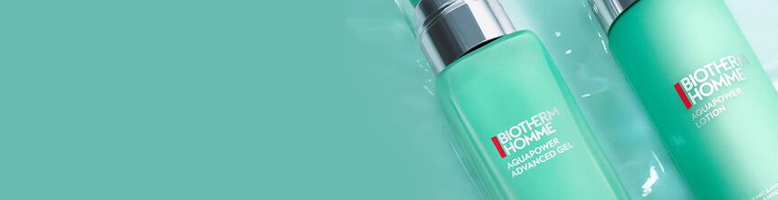 Two Biotherm Homme bottles with aqua green gradient design lying on glossy surface with matching green background.